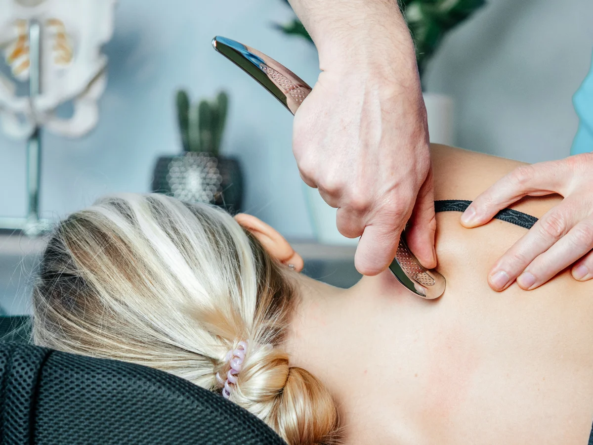 Close-up of an IASTM tool being scraped over the skin to release fascial restrictions
