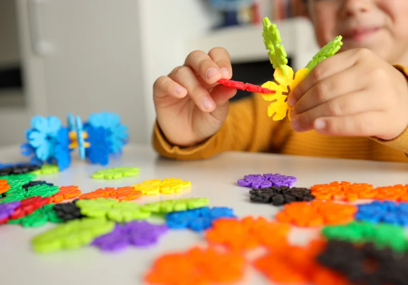 Child building with small construction pieces to develop hand strength and fine motor control