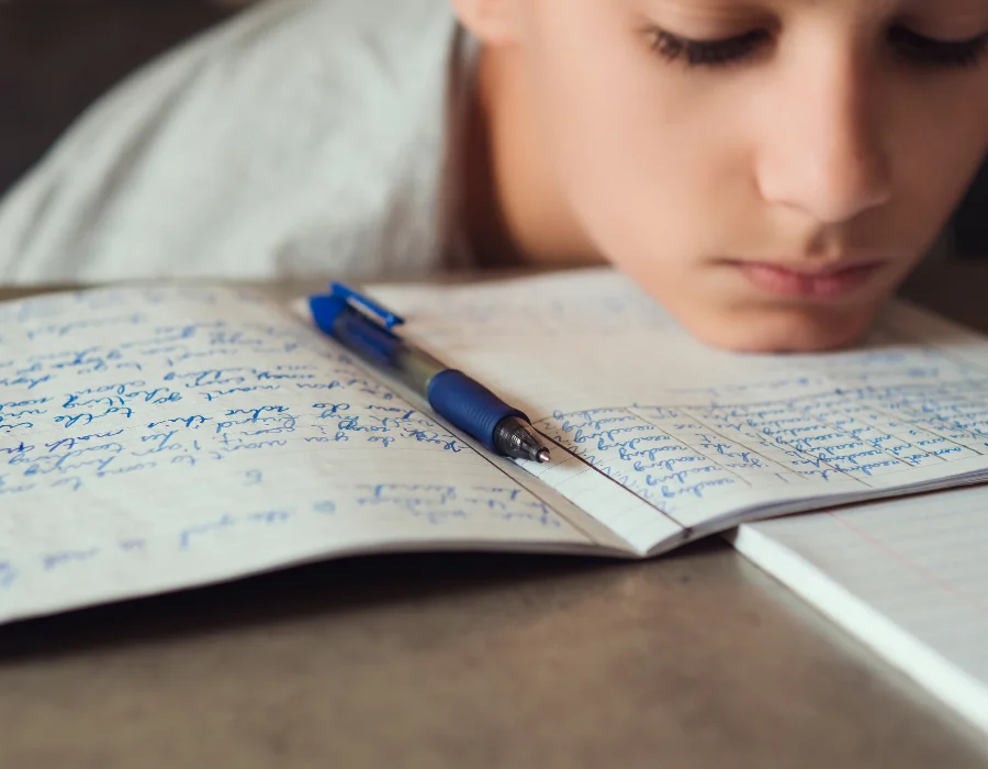 School-age child working closely over a notebook, showing the effort handwriting can demand