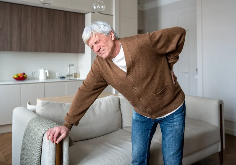 Older adult with back pain and limited mobility at home, suited to an online physiotherapy consultation