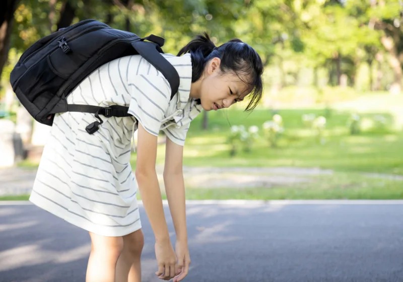 Student bending forward under the weight of a heavy backpack